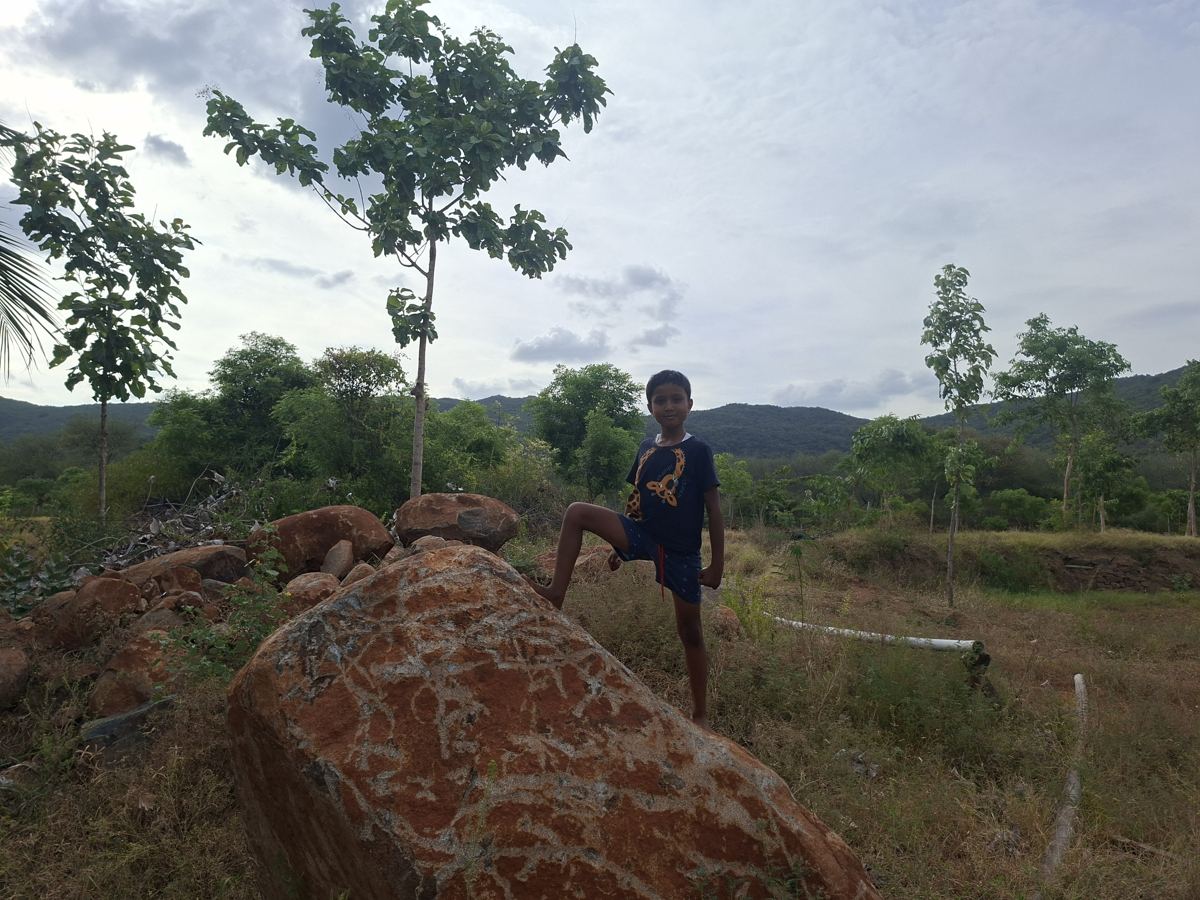 A boy standing on a rock with the hills behind him
